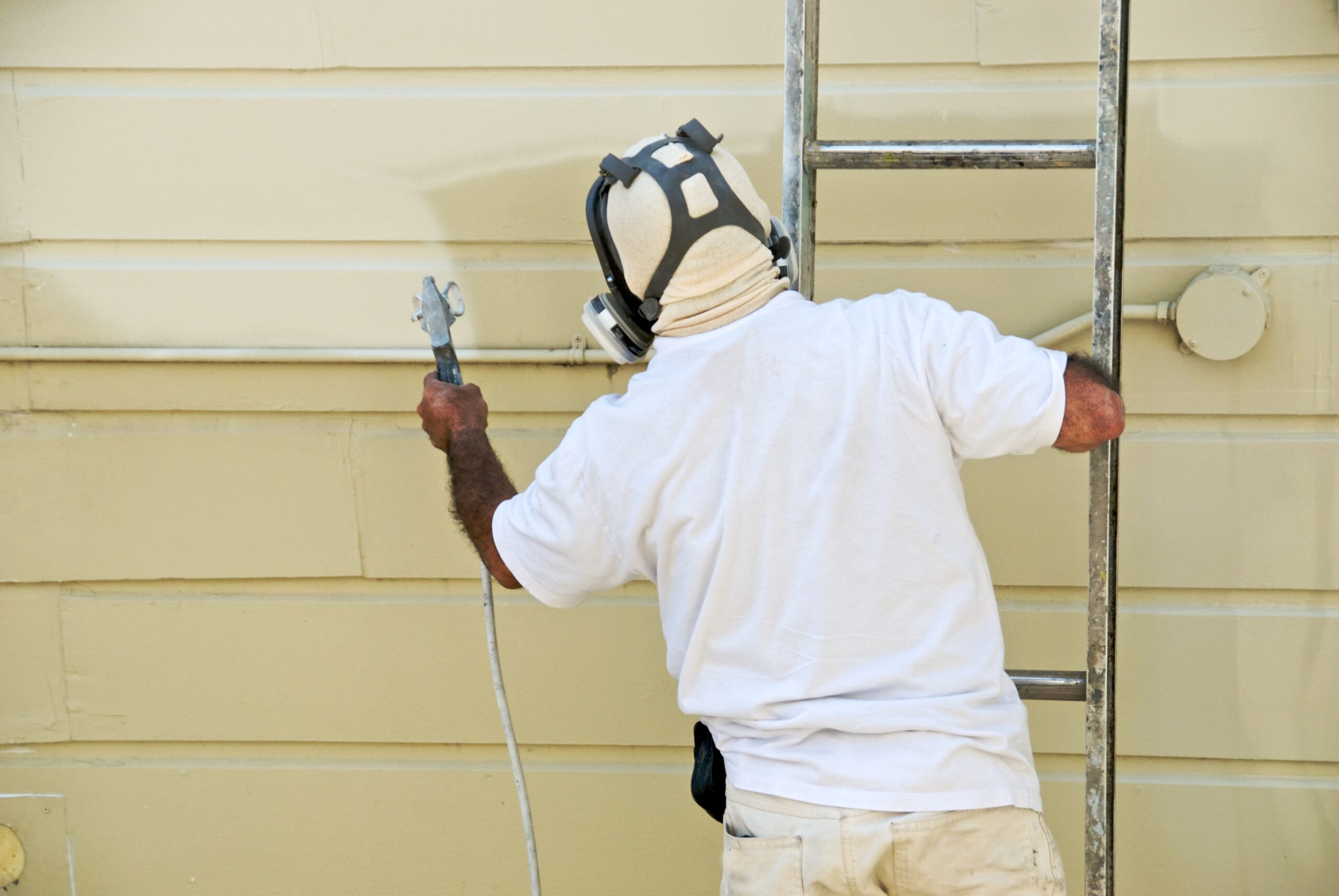 Castleton Service Group Painter spray painting exterior siding Castleton Service Group Painter spray painting exterior siding